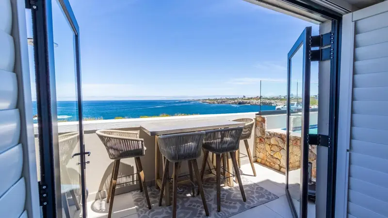 Terrasse avec table et chaises donnant sur la mer.