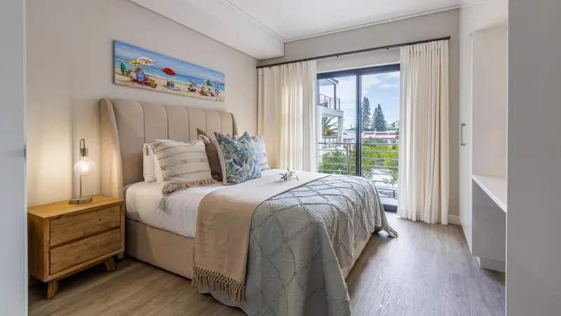 Une chambre lumineuse avec un grand lit et une décoration neutre.