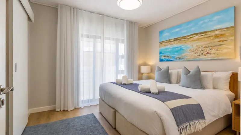 Une chambre lumineuse avec un grand lit et un tableau décoratif.