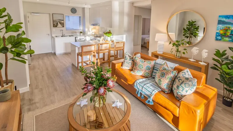 Un salon lumineux avec un canapé orange et une table basse en bois.