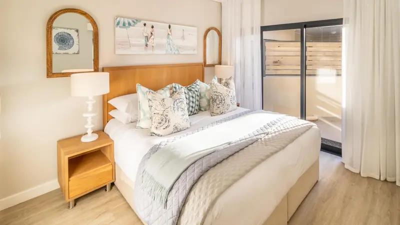 Une chambre lumineuse avec un grand lit recouvert d'une couette et de coussins.