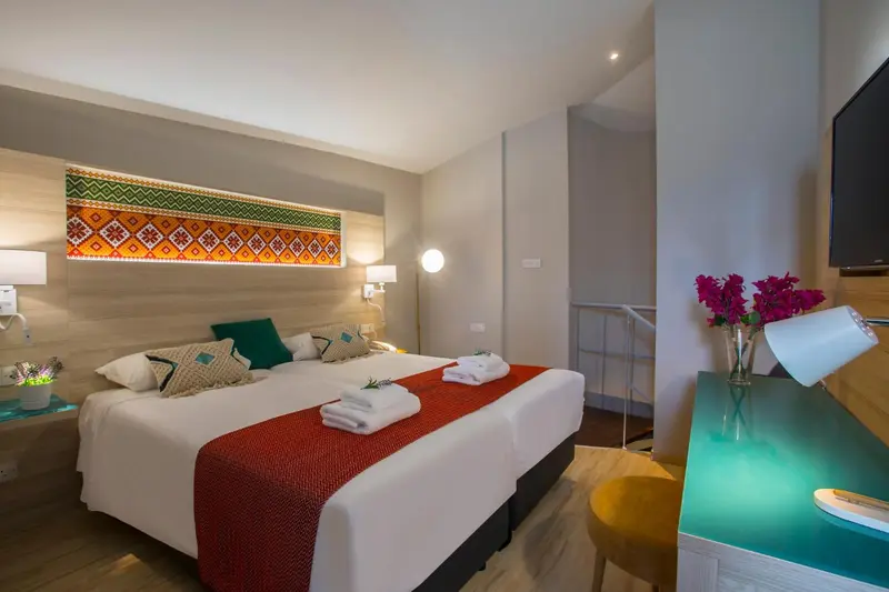 Chambre lumineuse avec un grand lit et une décoration colorée.