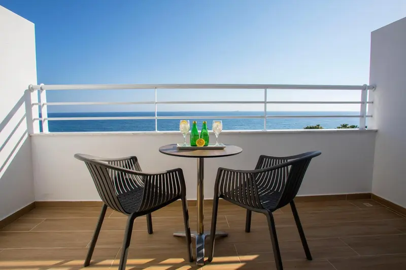 Terrasse avec table et chaises donnant sur la mer.