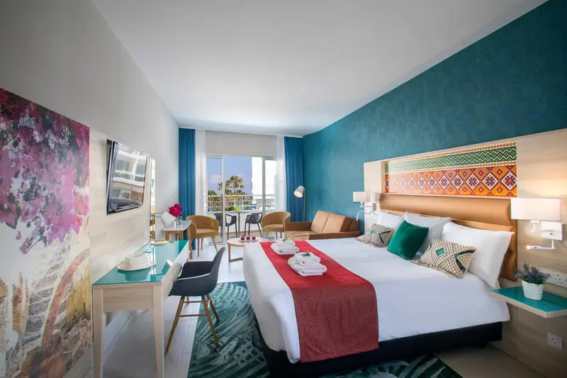 Chambre lumineuse avec un grand lit et un espace détente.