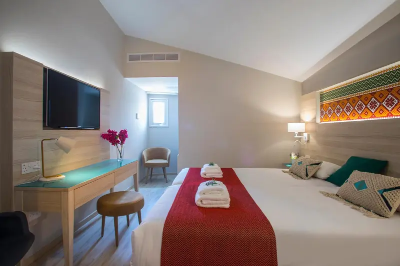Une chambre lumineuse avec un lit double et un espace bureau.