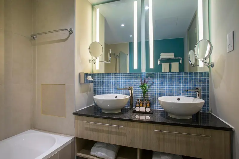 Une salle de bain moderne avec deux vasques et un grand miroir.