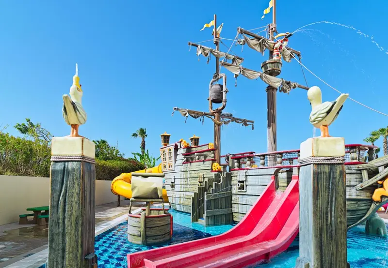 Structure de jeu en forme de bateau pirate avec toboggans et décorations d'oiseaux.