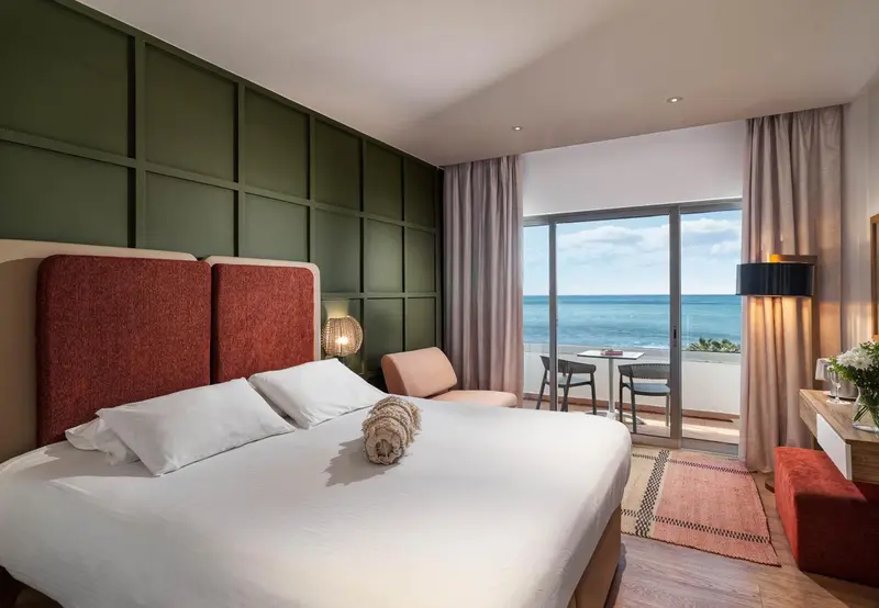 Une chambre lumineuse avec un grand lit et une vue sur la mer.