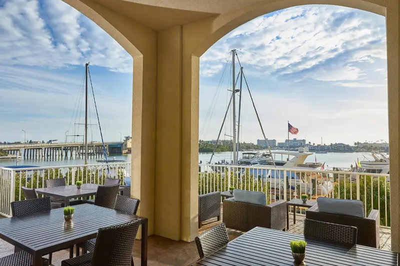 Terrasse ombragée donnant sur un port de plaisance ensoleillé.