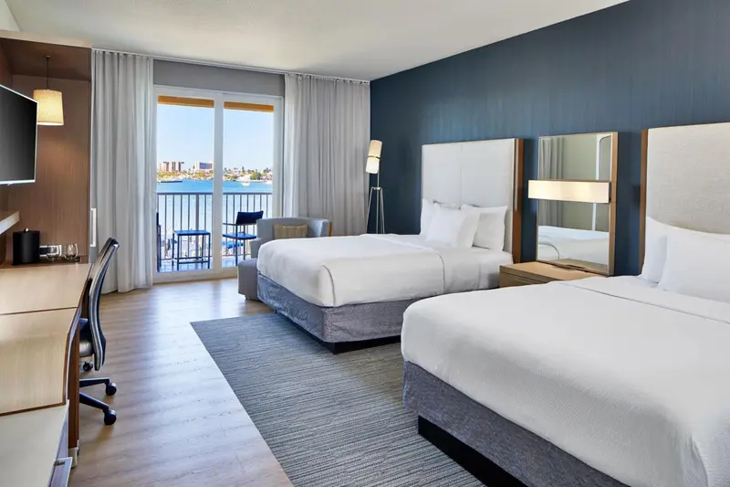 Une chambre lumineuse avec deux lits et une vue sur la mer.