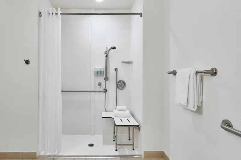 Une douche accessible avec un siège et des barres d'appui.