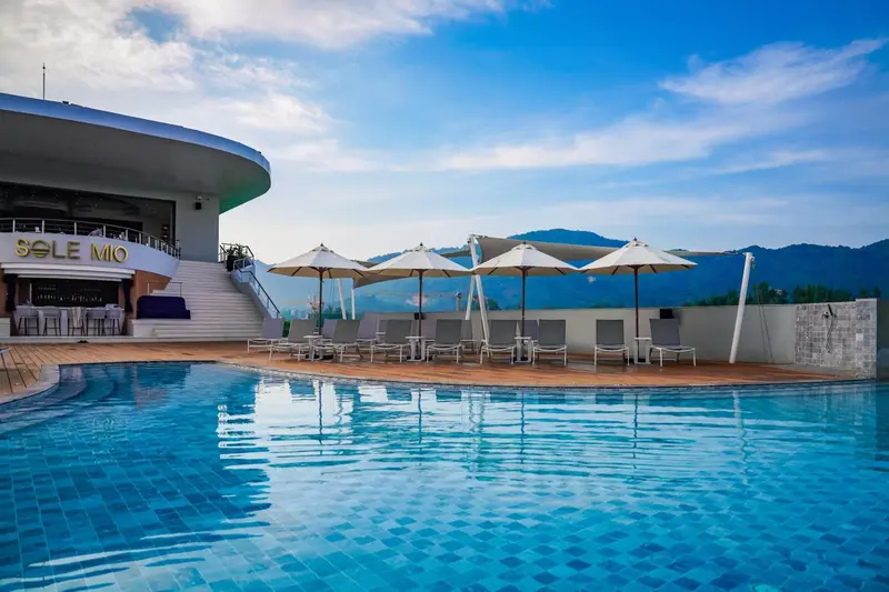 Terrasse avec parasols et piscine bleue au premier plan.