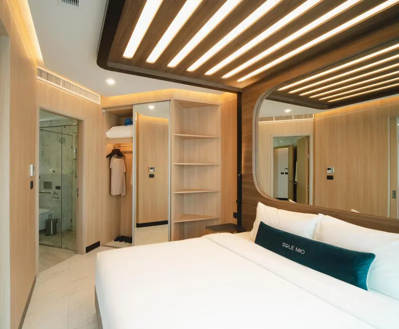 Une chambre lumineuse avec un lit blanc et un grand miroir.