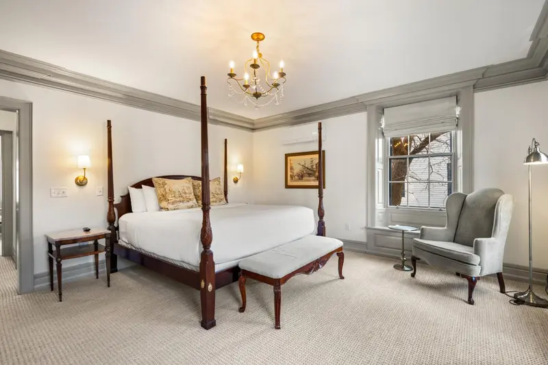 Une chambre lumineuse avec un grand lit à baldaquin et un fauteuil.