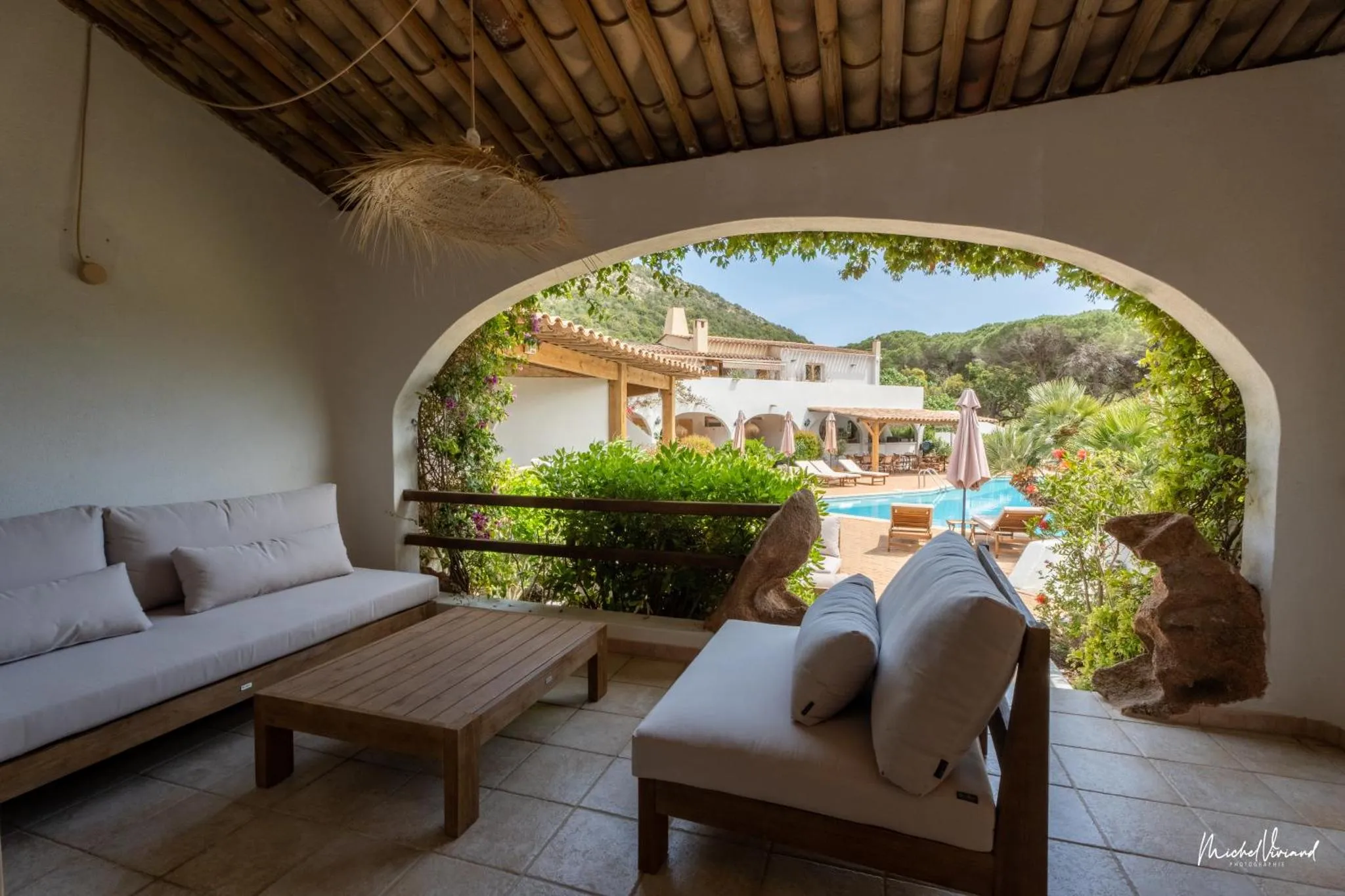 Espace de détente extérieur avec canapés et vue sur une piscine et un bâtiment.
