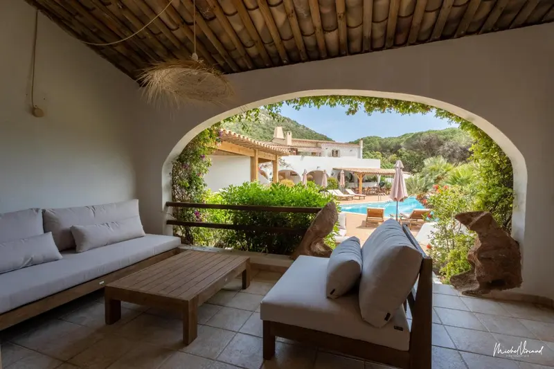 Espace de détente extérieur avec canapés et vue sur une piscine et un bâtiment.