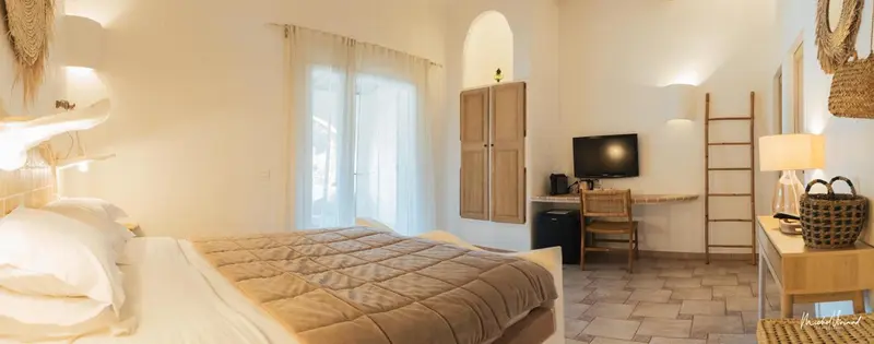 Une chambre lumineuse avec un grand lit et un espace bureau.