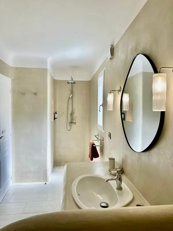 Une salle de bain lumineuse avec douche à l'italienne et vasque sur plan.