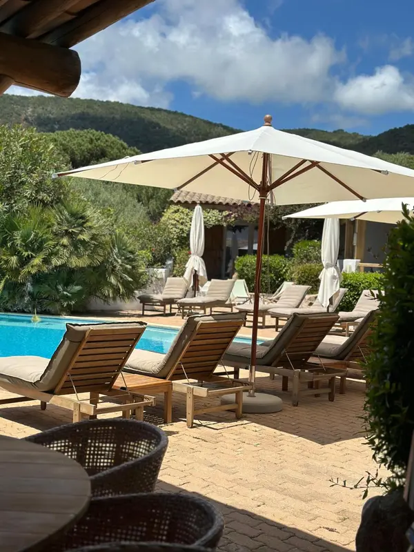 Transats et parasols ombragent une piscine bordée d'une terrasse.