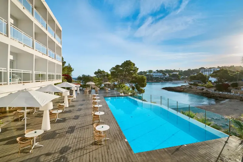 Terrasse avec tables et chaises près d'une piscine et vue sur la mer.