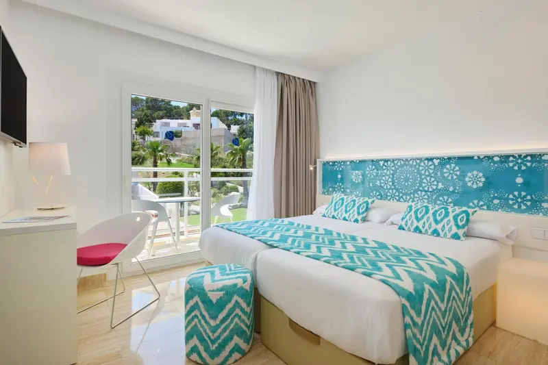 Une chambre lumineuse avec un grand lit et un accès à un balcon.
