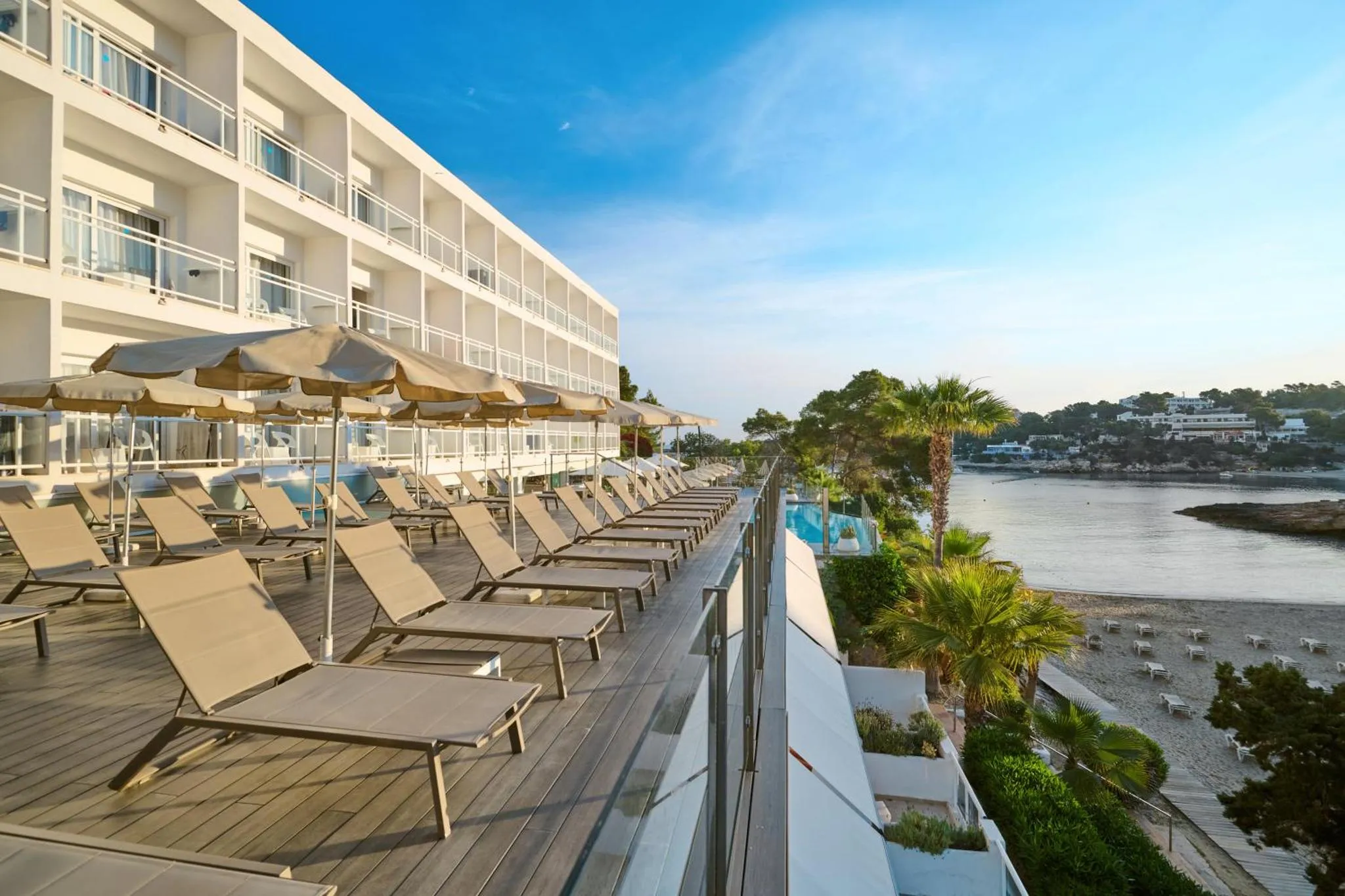 Terrasse ensoleillée avec transats et vue sur la mer.