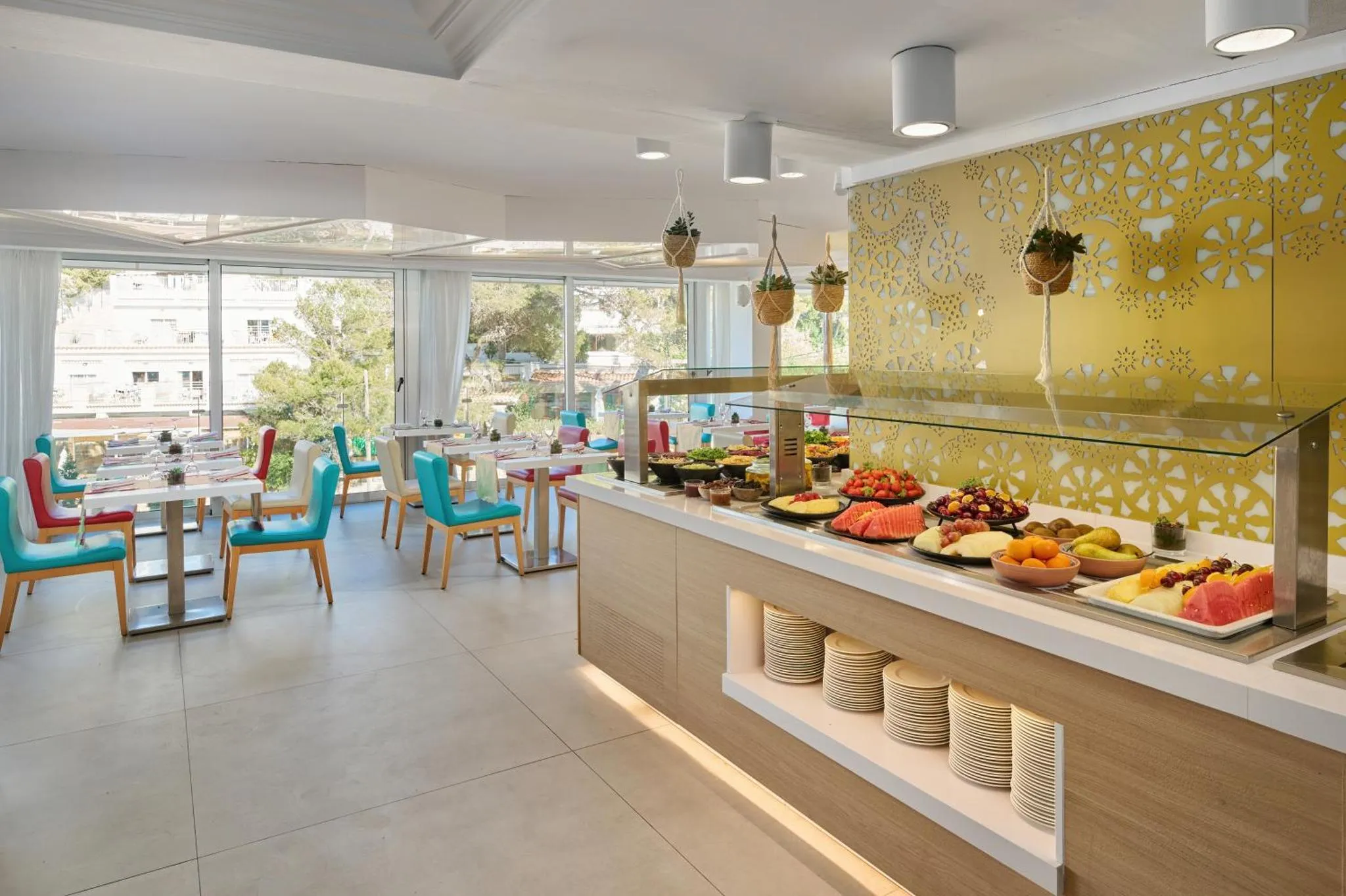 Une salle lumineuse avec un buffet garni de fruits frais et des tables à manger.