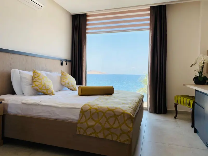 Une chambre lumineuse avec un grand lit donnant sur la mer.