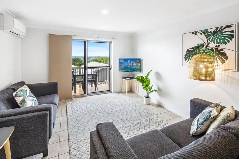 Un salon lumineux s'ouvre sur un balcon avec vue sur la mer.
