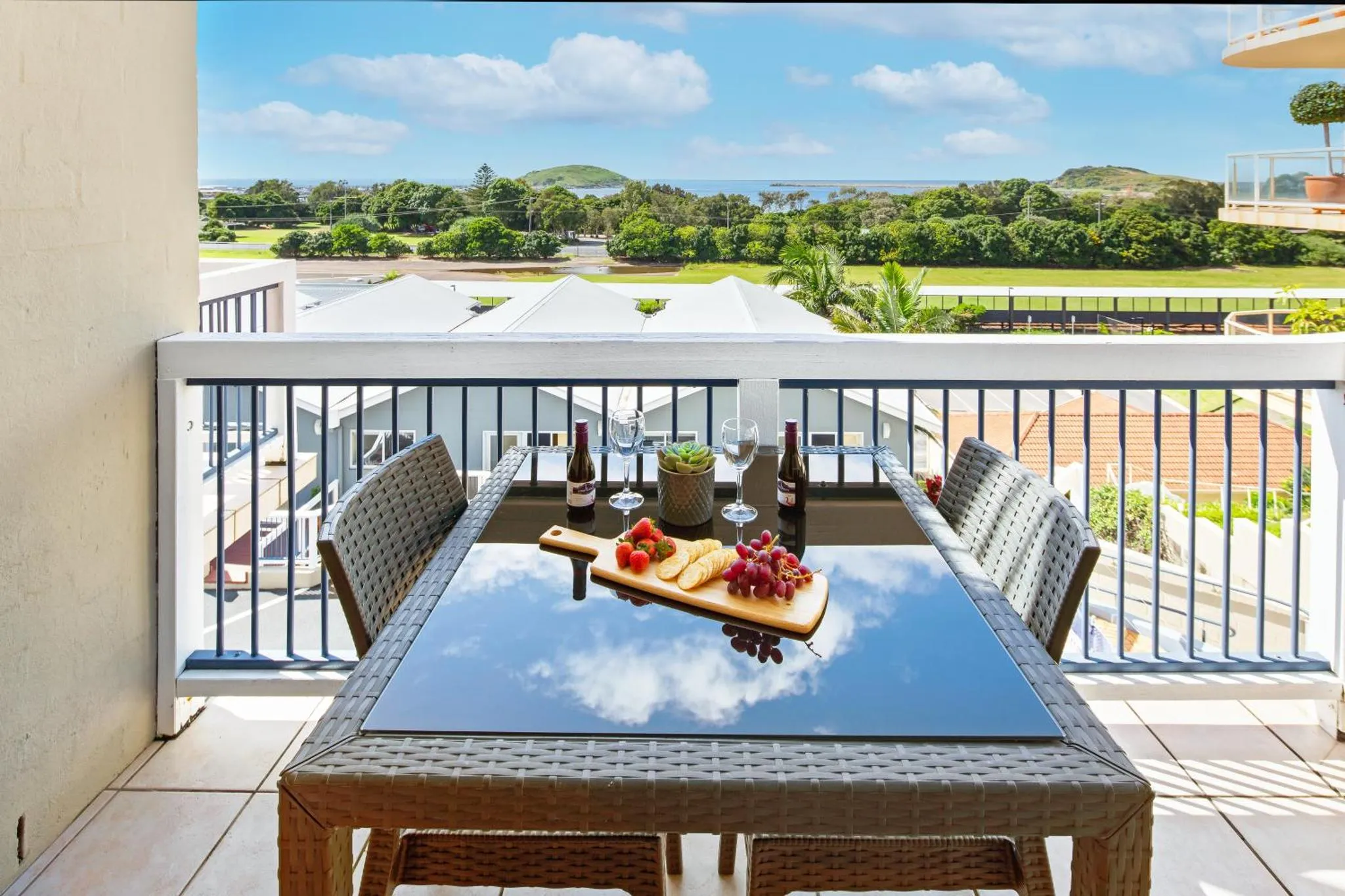 Une table est dressée sur une terrasse avec vue sur la mer et la végétation.