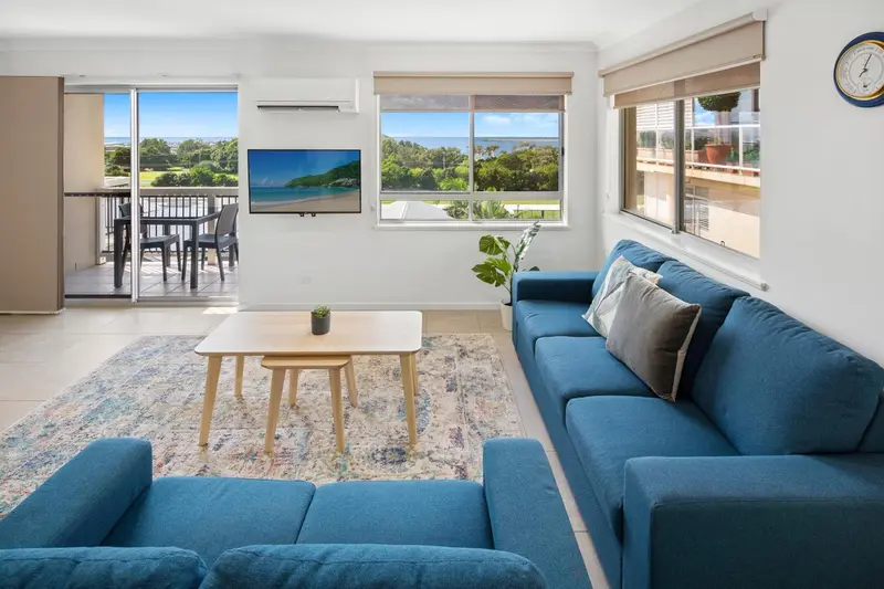 Un salon lumineux avec canapés bleus et vue sur la mer.