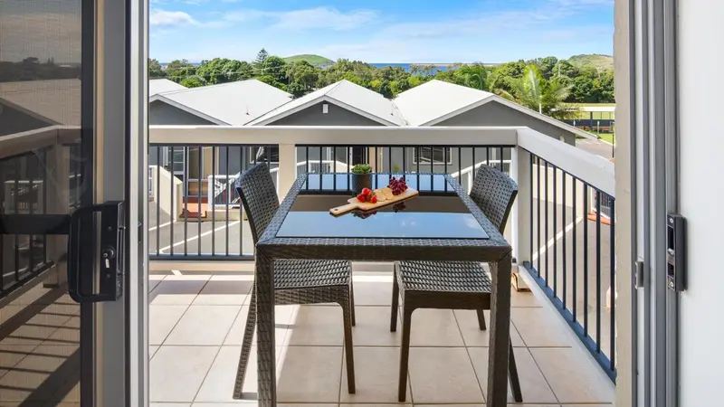 Une table avec des fruits est mise en scène sur une terrasse ensoleillée.