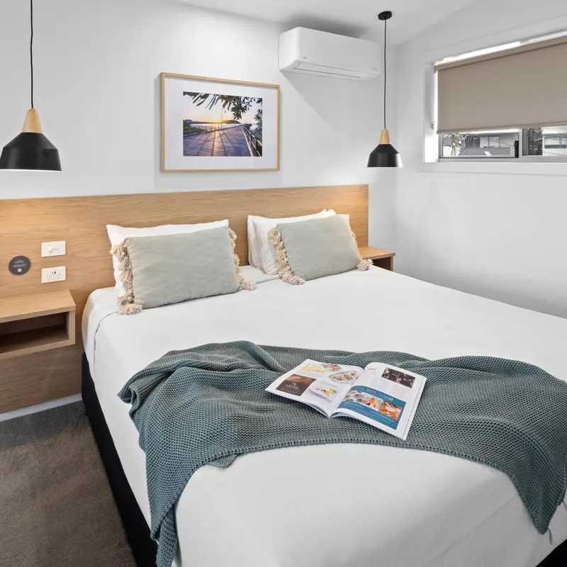 Une chambre lumineuse avec un grand lit recouvert d'une couverture bleue et de coussins verts.