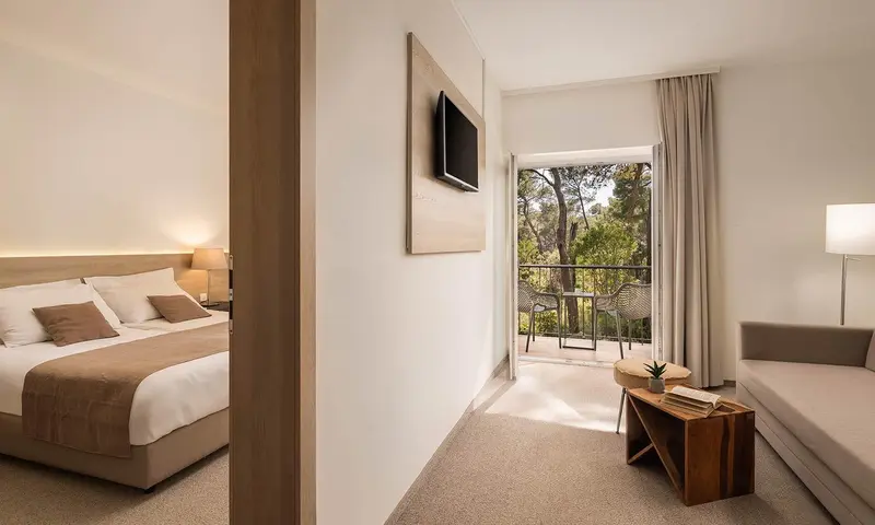 Une chambre lumineuse avec un lit et un espace salon donnant sur une terrasse.