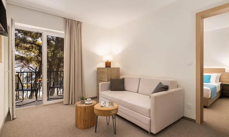 Espace de séjour lumineux avec canapé et accès à un balcon.