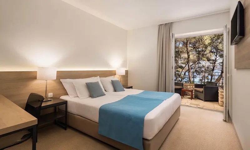 Une chambre lumineuse avec un grand lit et un accès à une terrasse.