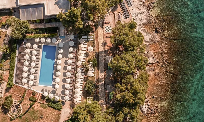 Vue aérienne d'une piscine et d'une plage bordée de parasols.