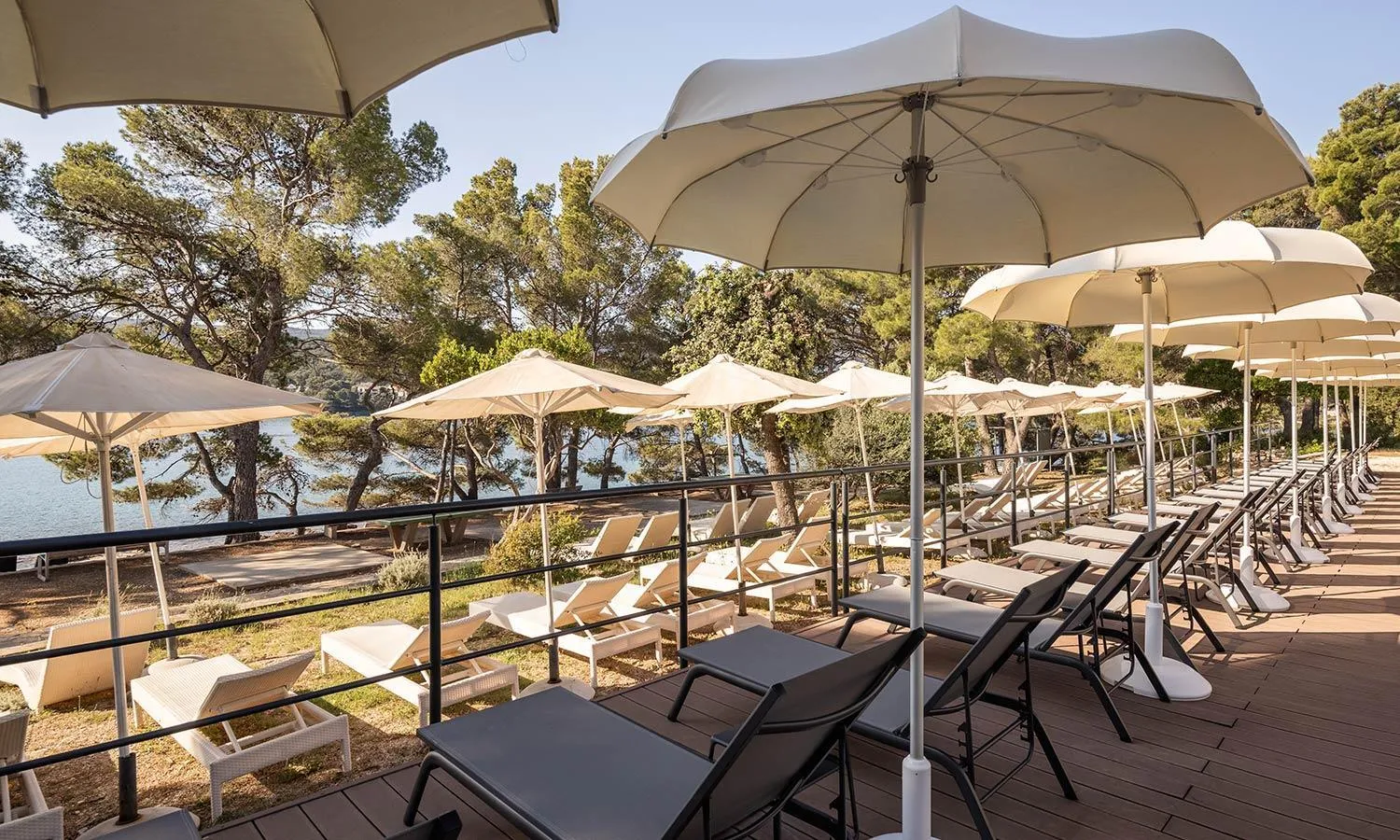 Terrasse aménagée avec transats et parasols face à la mer.
