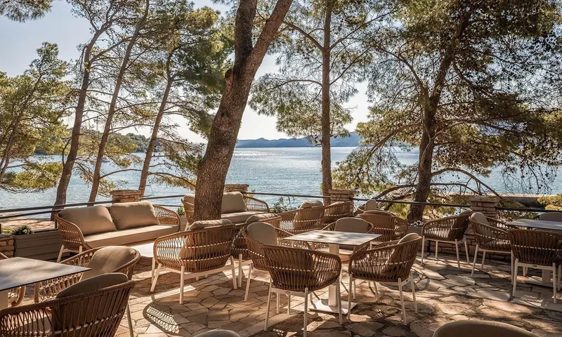 Terrasse aménagée avec des canapés et des tables en osier face à la mer.
