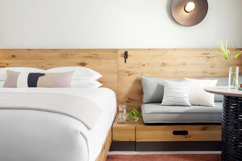 Un lit avec des oreillers blancs et des coussins décoratifs se trouve devant une tête de lit en bois.