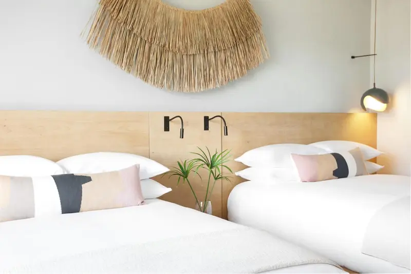 Une chambre lumineuse avec un grand lit et une décoration murale en fibres naturelles.