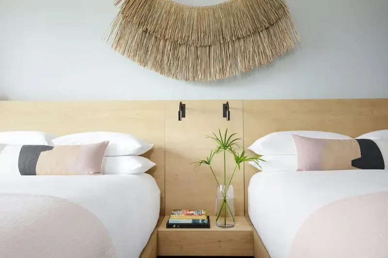 Lit double avec oreillers blancs et coussins décoratifs dans une chambre lumineuse.