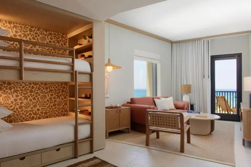 Une chambre lumineuse avec un canapé et un lit superposé.