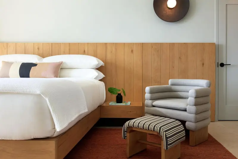 Une chambre lumineuse avec un grand lit et un fauteuil design.