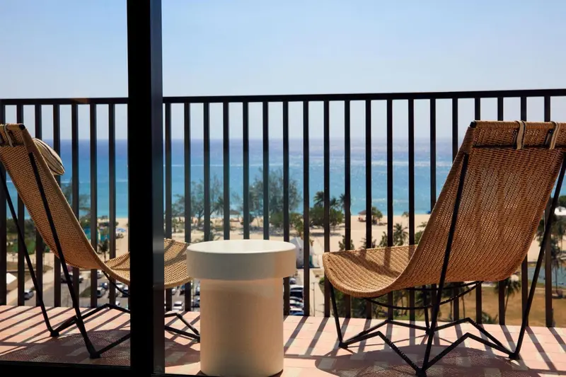 Deux fauteuils en osier sur une terrasse avec vue sur la mer.