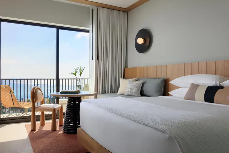 Une chambre lumineuse avec un grand lit et une vue sur la mer.