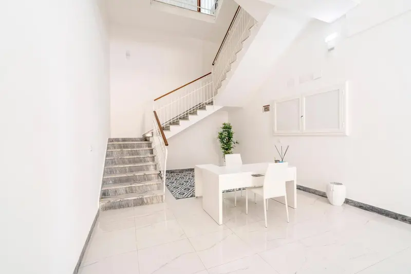 Un hall d'entrée lumineux avec un escalier et un comptoir d'accueil.