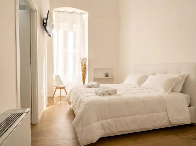 Une chambre lumineuse avec un grand lit blanc et une décoration minimaliste.