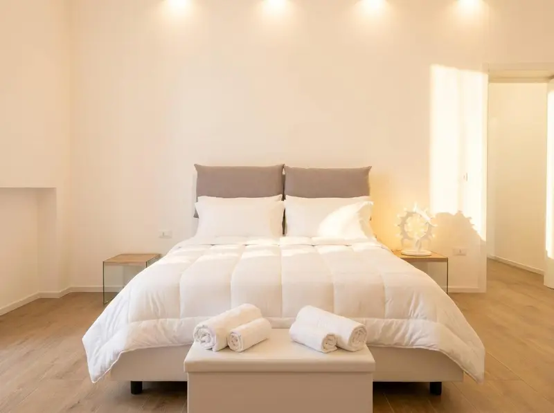 Une chambre lumineuse avec un grand lit recouvert d'une couette blanche.