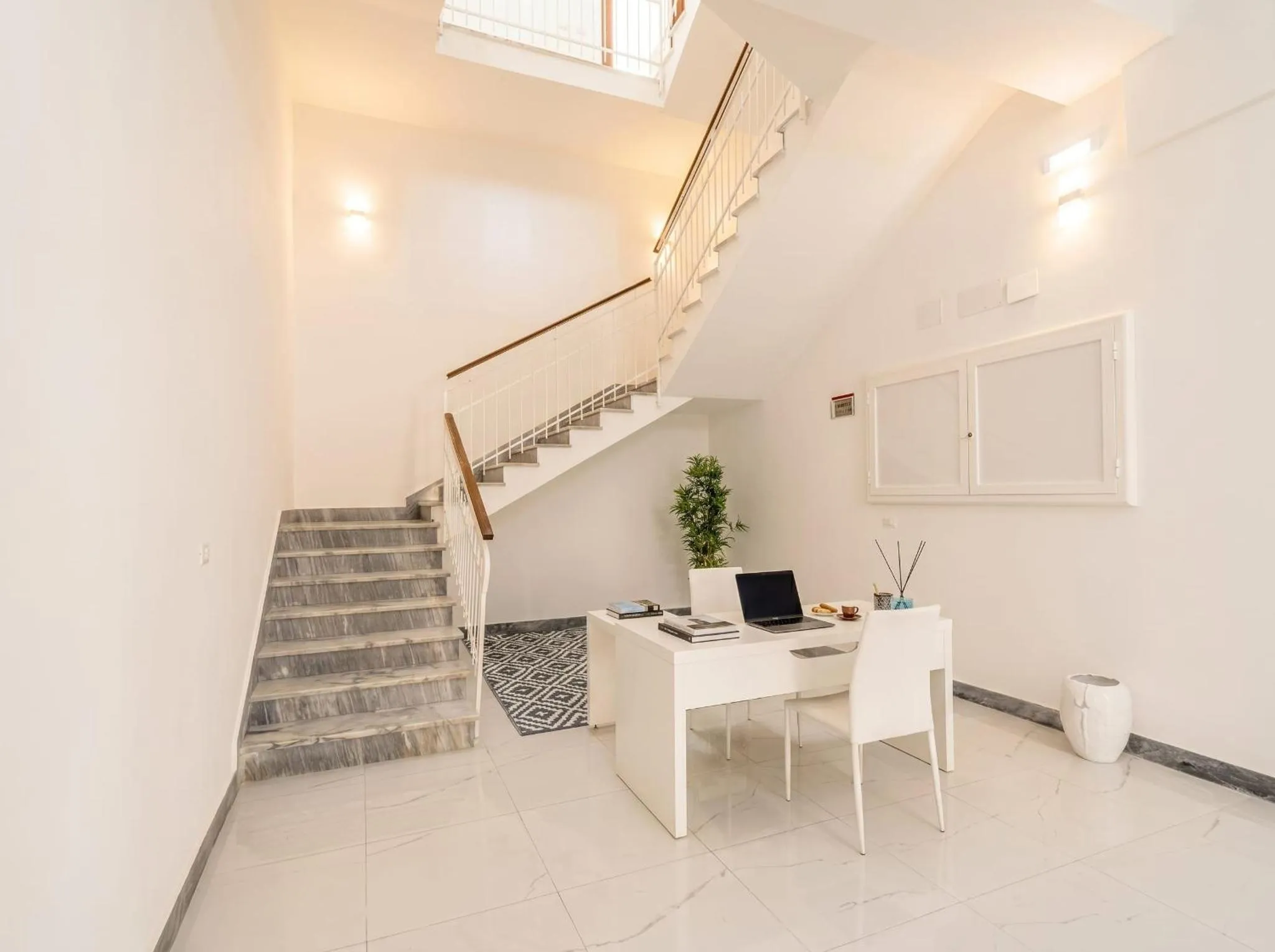 Un bureau blanc est installé au pied d'un escalier en pierre.